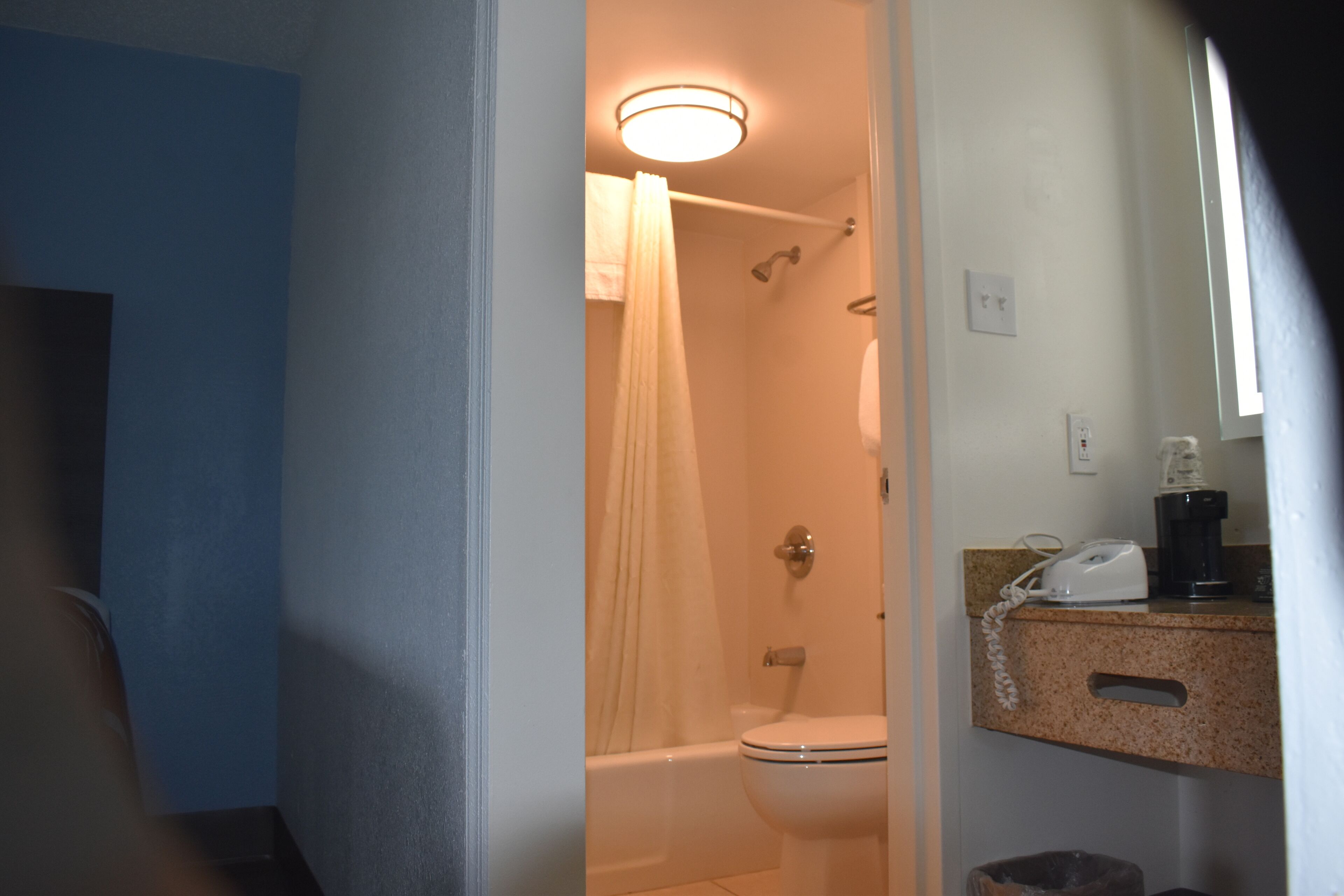 A bathroom with a bathtub, toilet, and a coffee maker on the counter.
