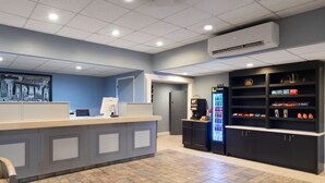 Zona de recepción con mostrador, refrigerador lleno de bebidas y una exhibición de aperitivos.
