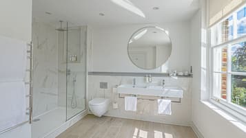 Une salle de bain moderne avec une douche à parois de verre, des toilettes, un meuble-lavabo à deux vasques et un grand miroir.