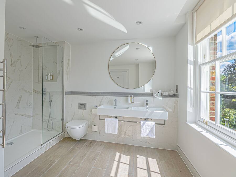 Une salle de bain moderne avec une douche à parois de verre, des toilettes, un meuble-lavabo à deux vasques et un grand miroir.
