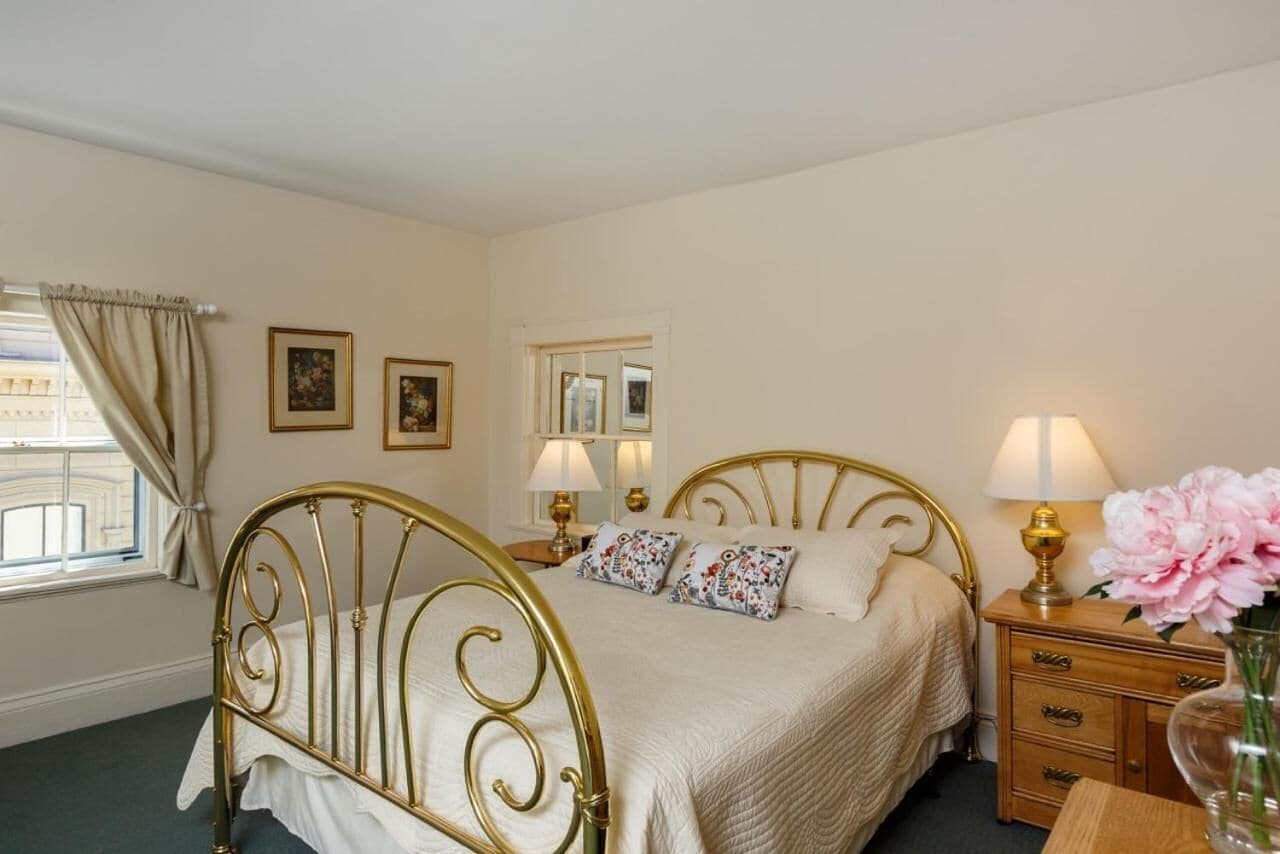 A bedroom with a gold metal bed frame, a bedside table with lamps, and a mirror on the wall.