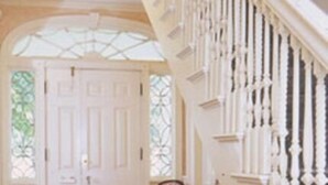 A grand staircase with white balusters and a patterned rug leading to a door with glass panels. - The Salem Inn (Salem)