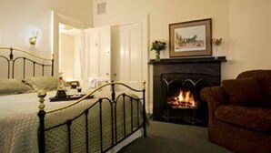 A bedroom with a bed, a fireplace, a sofa, and a framed picture on the wall. - The Salem Inn (Salem)