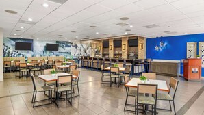 Un restaurant spacieux avec de nombreuses tables et chaises, un bar et un mur d’accent bleu.