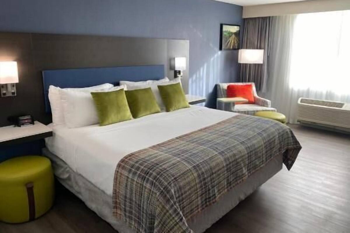 Een hotelkamer met een bed, nachtkastjes, een stoel, een lamp en een raam.