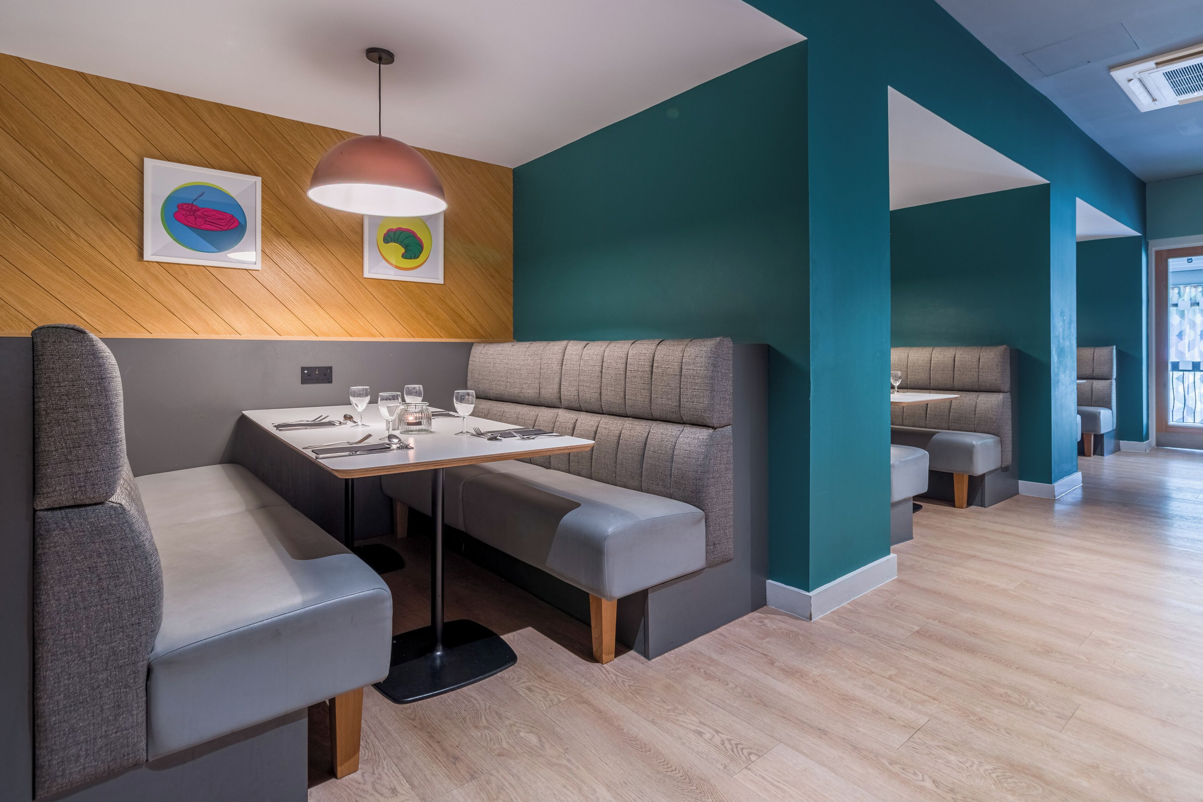 A modern restaurant interior with booth seating and a long communal table.