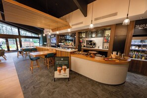 A modern coffee shop with a bar area, seating, and a menu board.