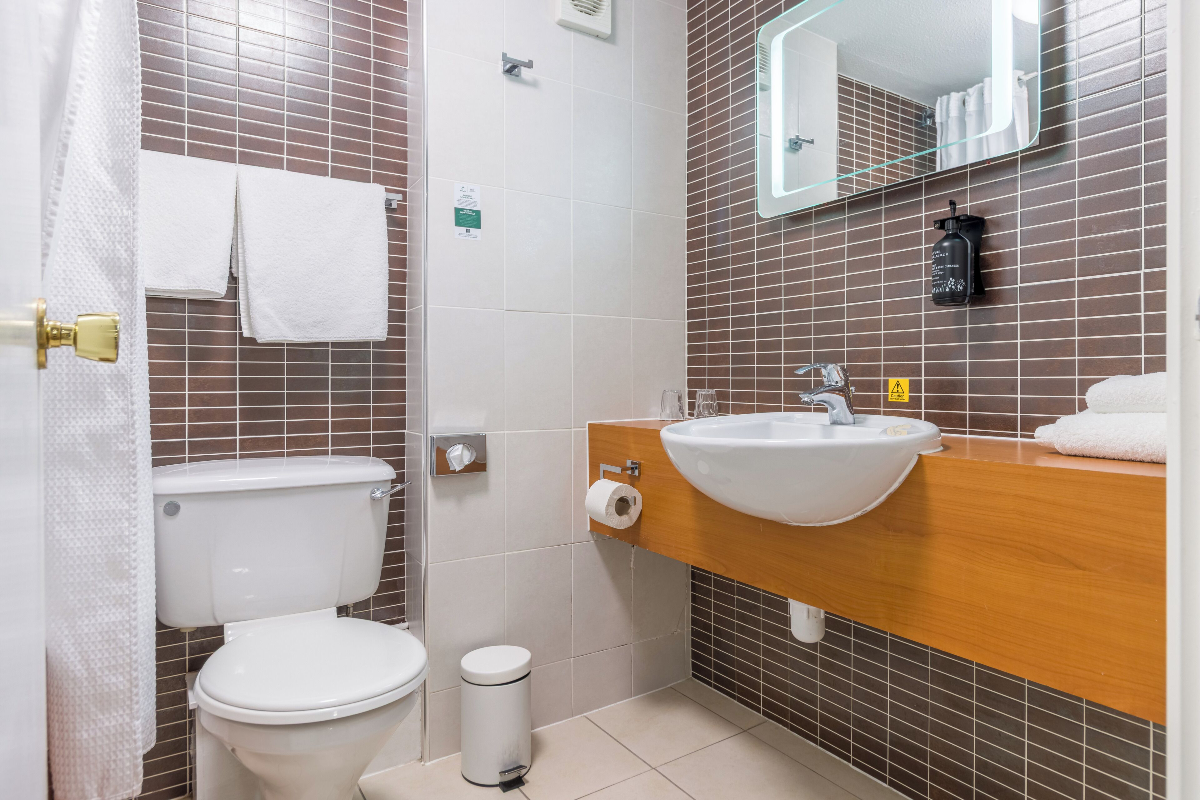 A bathroom with a toilet, sink, and mirror.