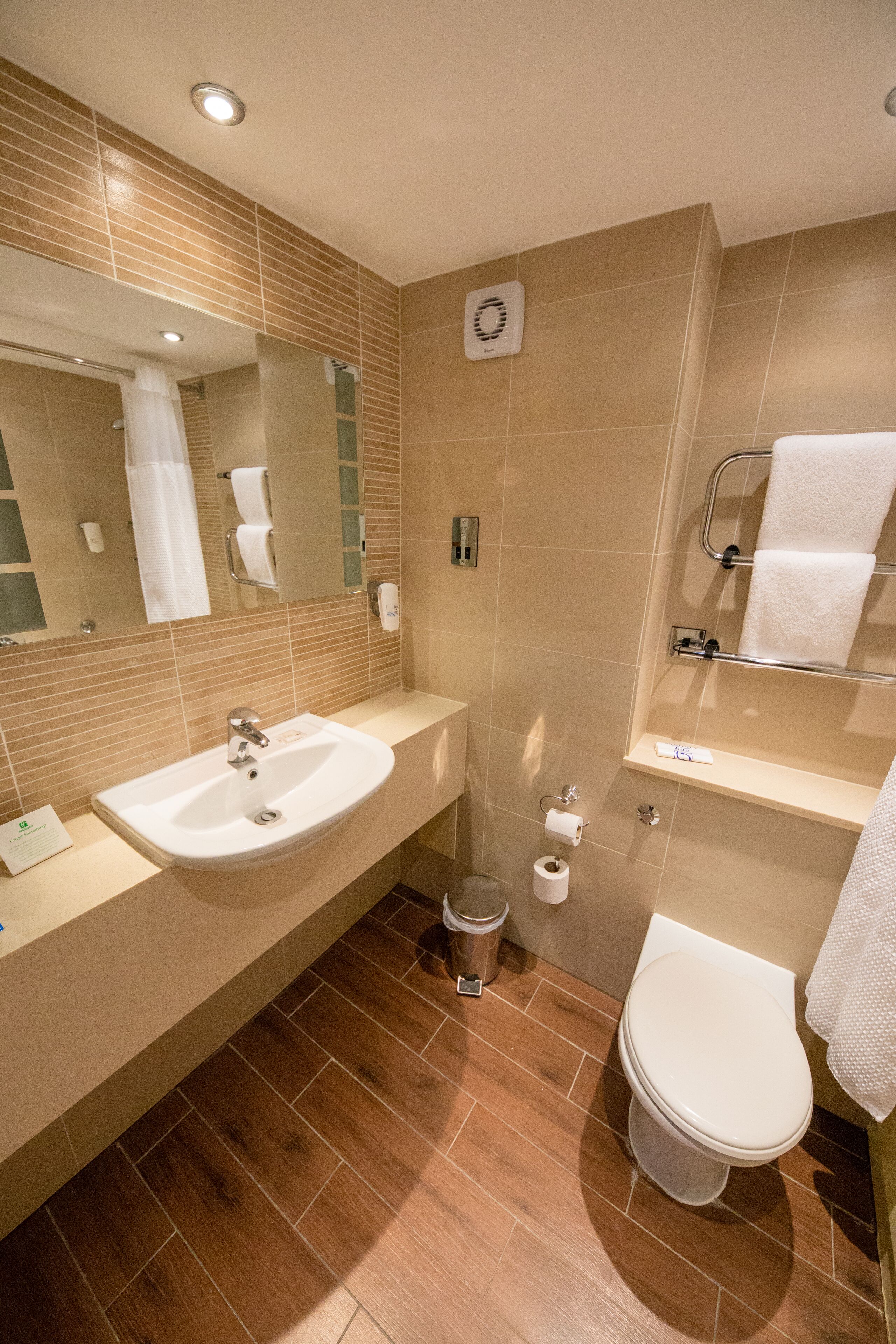 Un baño moderno con lavamanos, espejo, inodoro y toallero.