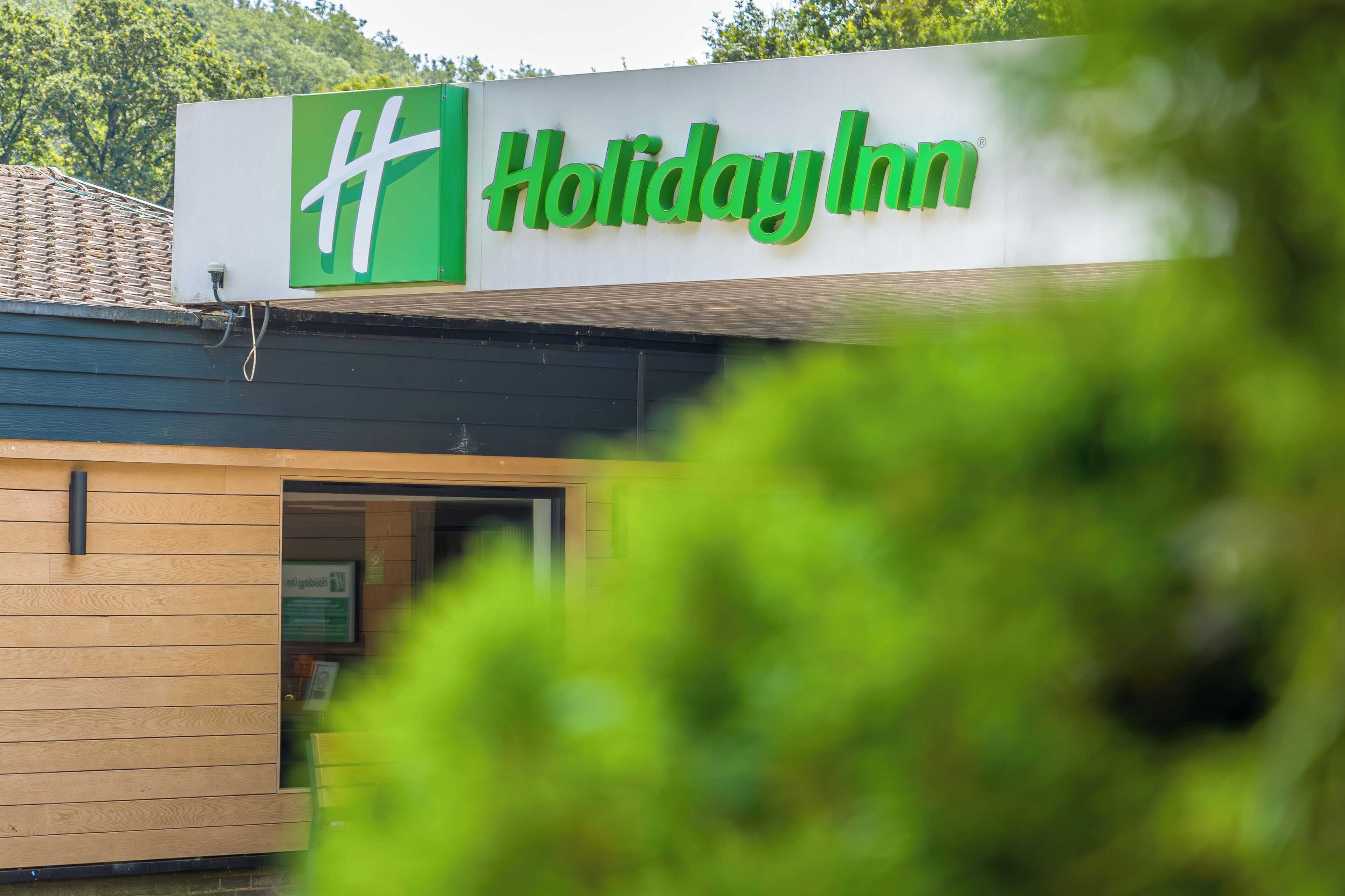 Une enseigne Holiday Inn avec un logo vert et le nom écrit en lettres blanches.