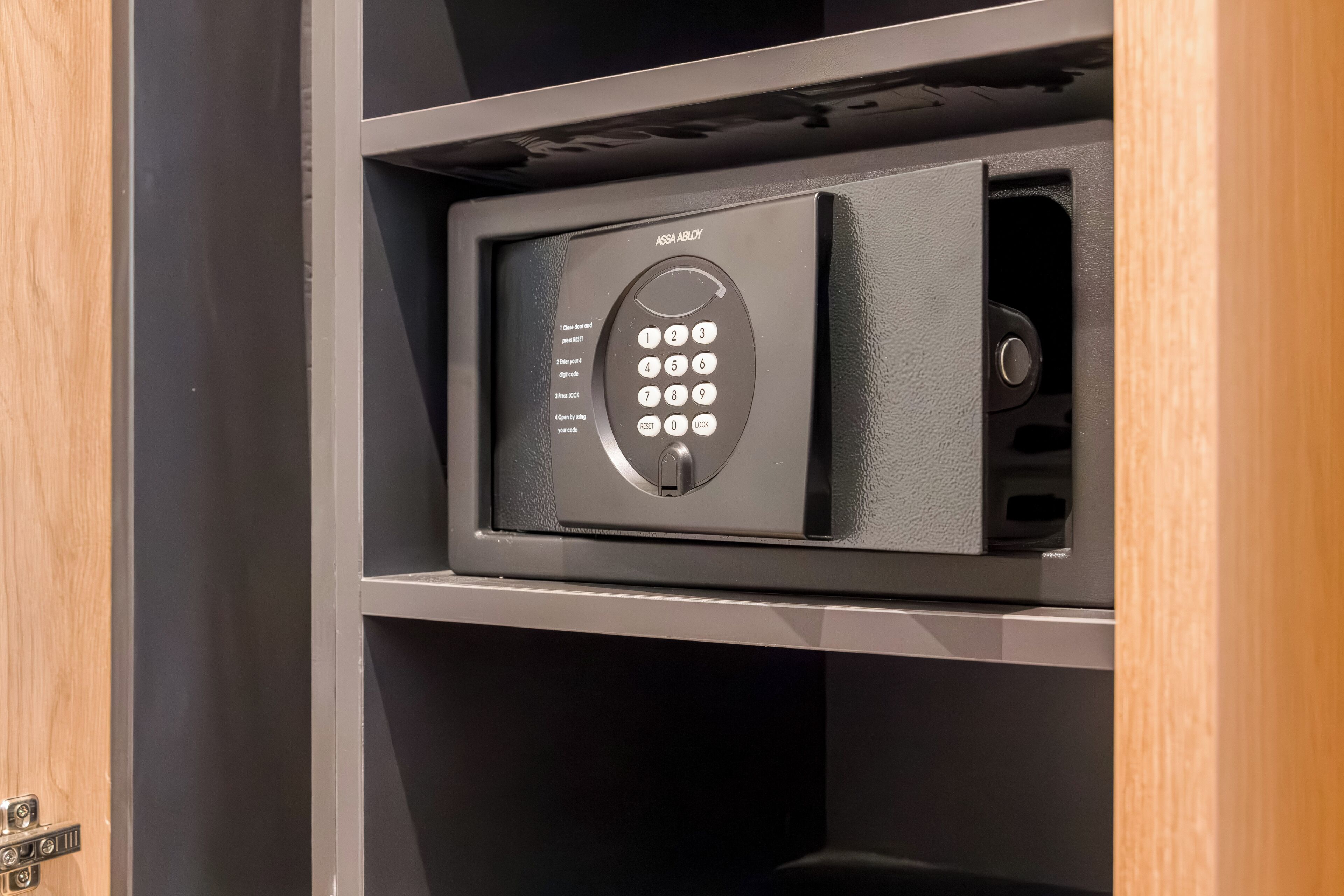 A secure safe with a keypad, placed in a wooden cabinet.