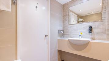 Baño con puerta blanca, lavamanos y espejo.