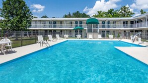 A rectangular swimming pool with clear blue water, surrounded by white lounge chairs and umbrellas. - Days Inn by Wyndham Cullman (Cullman)