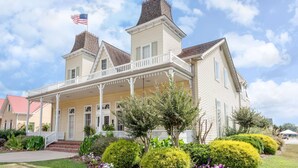 A large, two-story house with a porch and a chimney, featuring American flags on top. - Days Inn by Wyndham Cullman (Cullman)