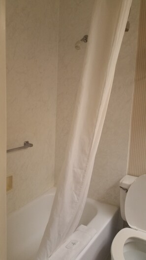 A bathroom with a bathtub, toilet, and shower curtain. - Clarion Hotel Downtown (Columbia)