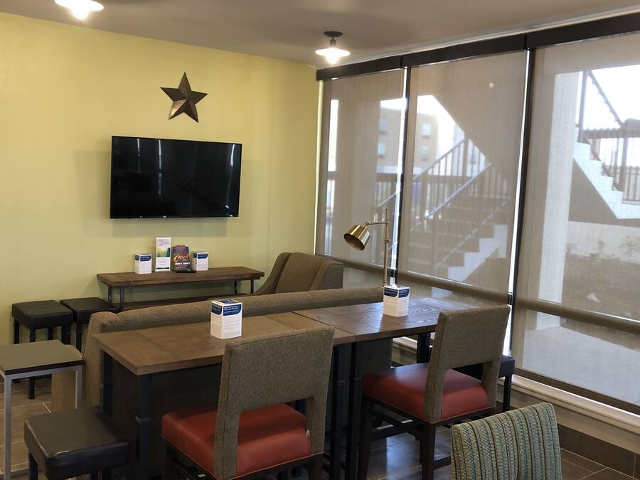 A restaurant with booths, tables, and chairs, a star decoration on the wall, and a TV mounted above the seating area.