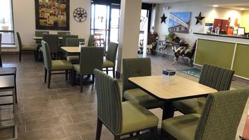 A restaurant interior with booths and tables, a mural on the wall, and a counter with a menu.