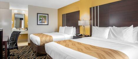 A hotel room with two beds, a desk, a chair, a lamp, and a painting on the wall.