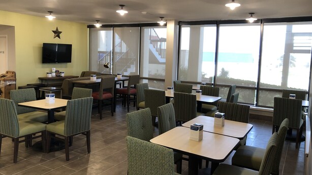 A restaurant with tables and booths, a television on the wall, and large windows with a view.
