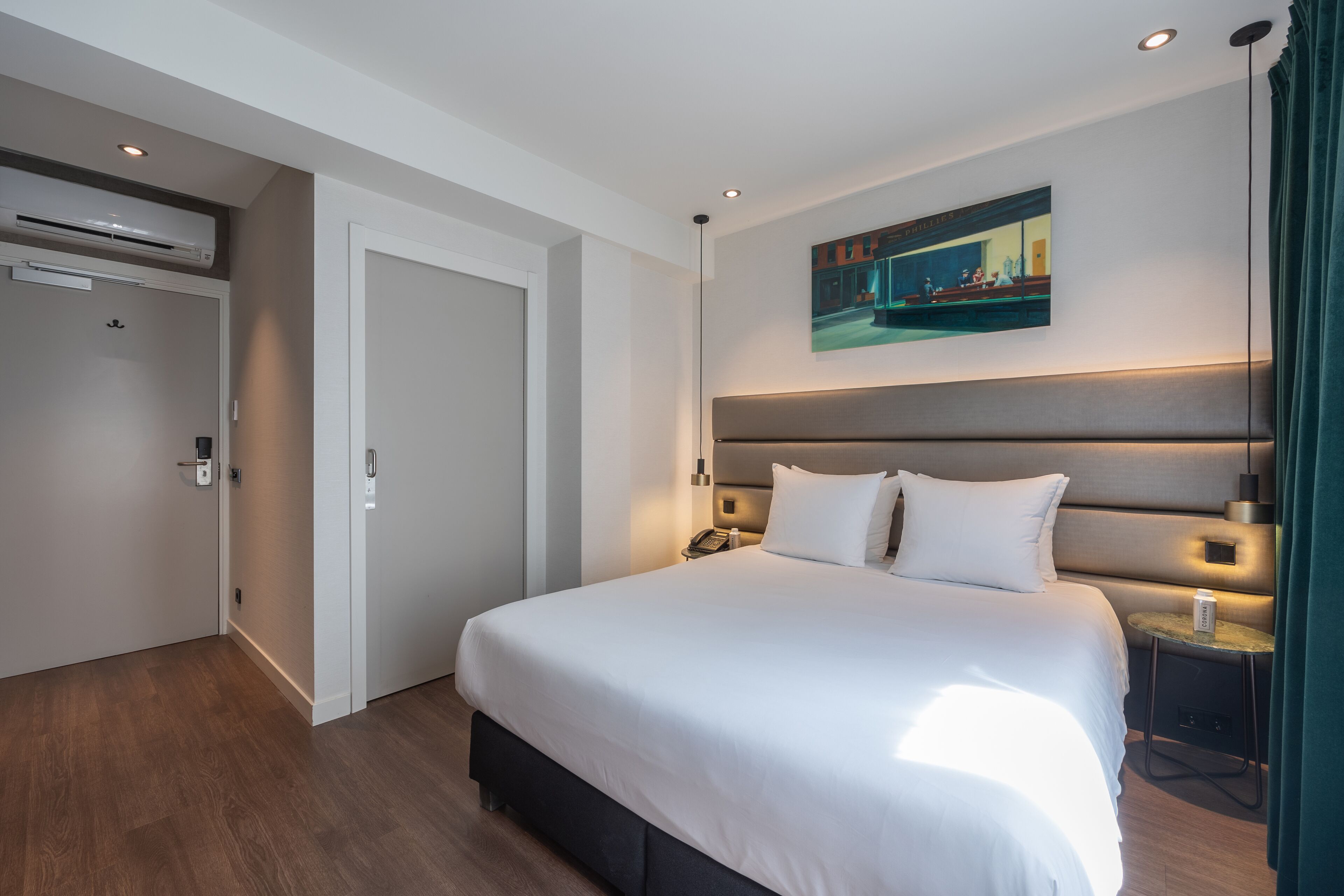 Et moderne hotelværelse med en stor seng, et maleri på væggen og et lille bord med en lampe.