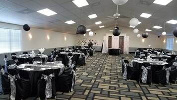 A banquet hall with tables set for a formal event, featuring a patterned carpet and ceiling lights.
