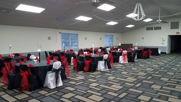 Un salón de conferencias con mesas dispuestas en filas, cada una cubierta con un mantel negro y cintas rojas.