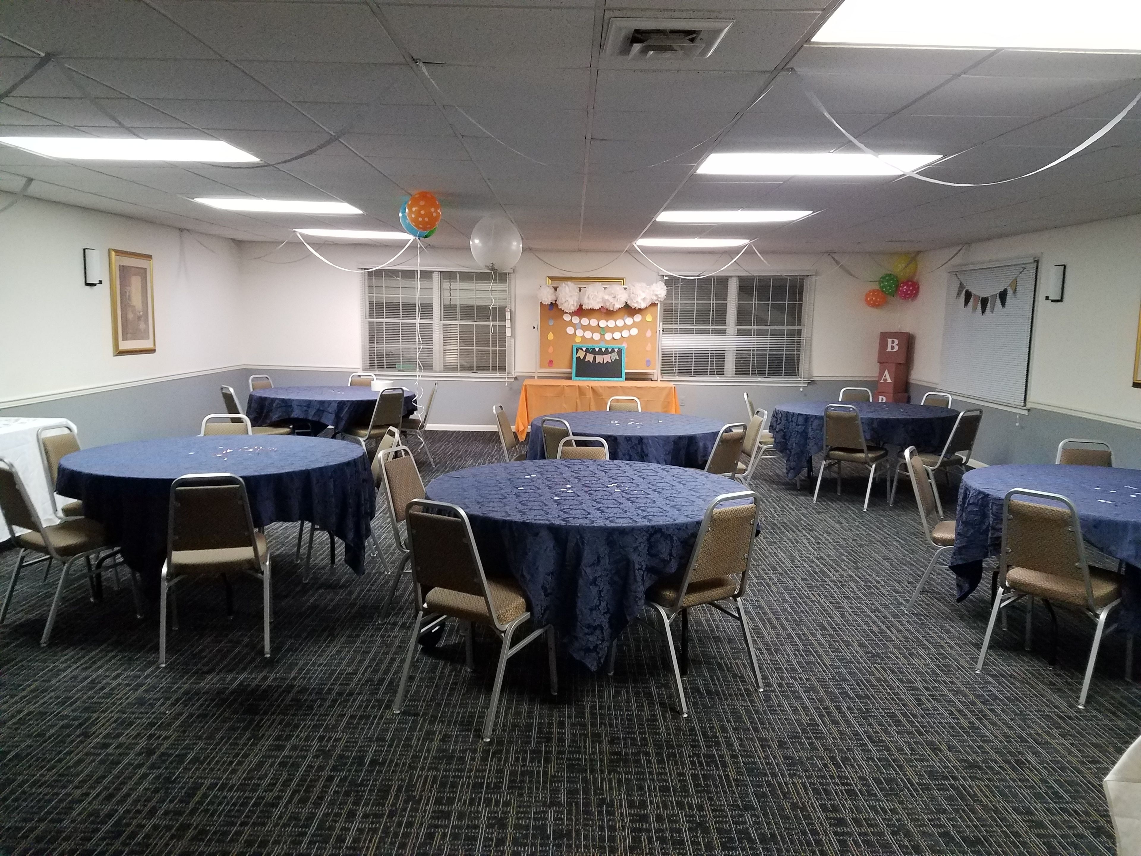 A conference room with round tables and chairs, a podium, and a banner on the wall.
