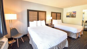 A hotel room with two beds, a chair, and a painting on the wall. - St Michaels Inn (St. Michaels)