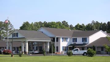 A motel with a covered front porch, a flagpole with an American flag, and a white pickup truck parked in front.