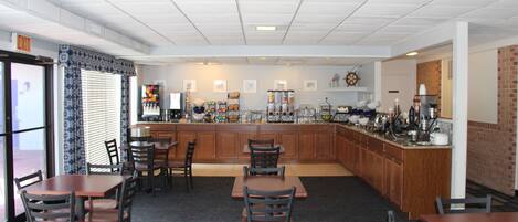 A restaurant with a bar area, multiple seating arrangements, and a kitchen visible in the background.