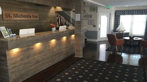 A reception desk with a wooden finish, a sign reading "St. Michaels Inn", and a staircase leading to upper floors. - St Michaels Inn (St. Michaels)