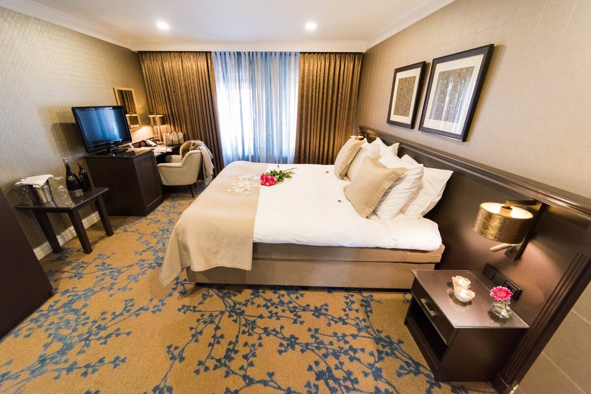 Une chambre d’hôtel avec un grand lit, un bureau avec une télévision, une chaise et une table de chevet avec une lampe.