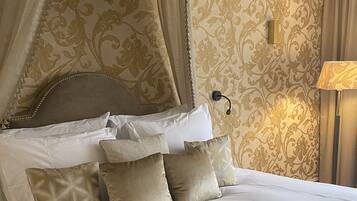 A four-poster canopy bed with multiple pillows, a headboard with bead trim, and a wall-mounted lamp.