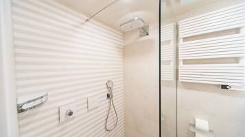 A modern bathroom with striped walls, a glass shower enclosure, and a towel rack.