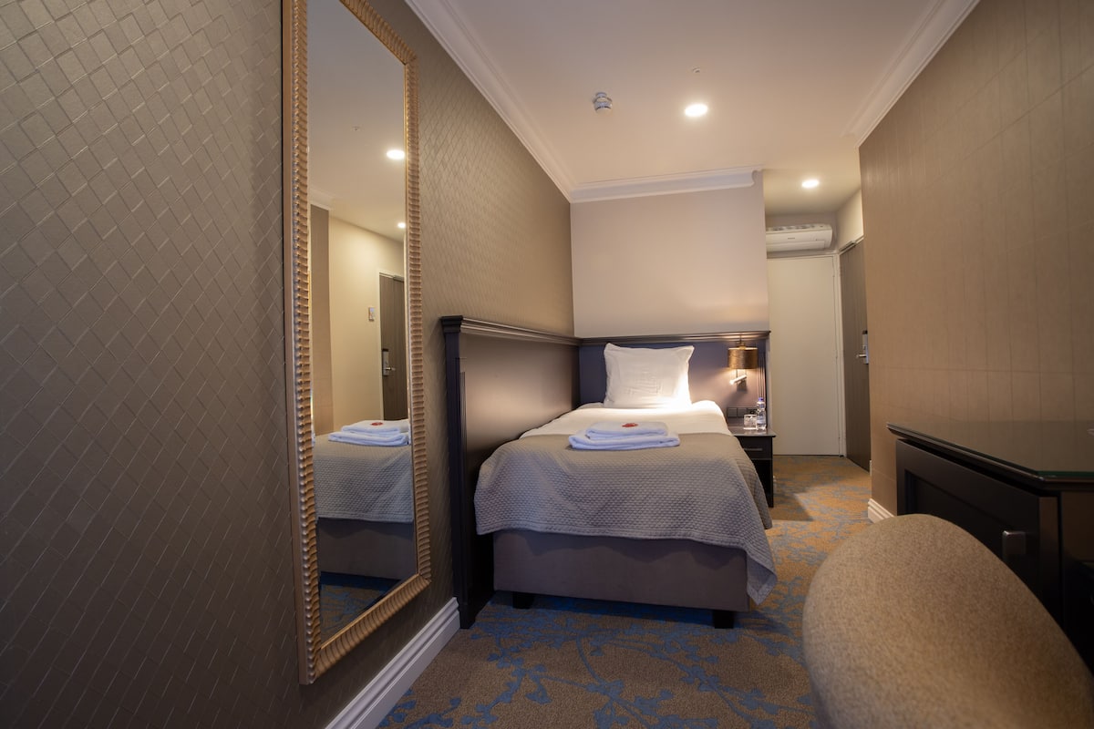 Une chambre d’hôtel avec un grand lit, une table de chevet, un miroir et une chaise.