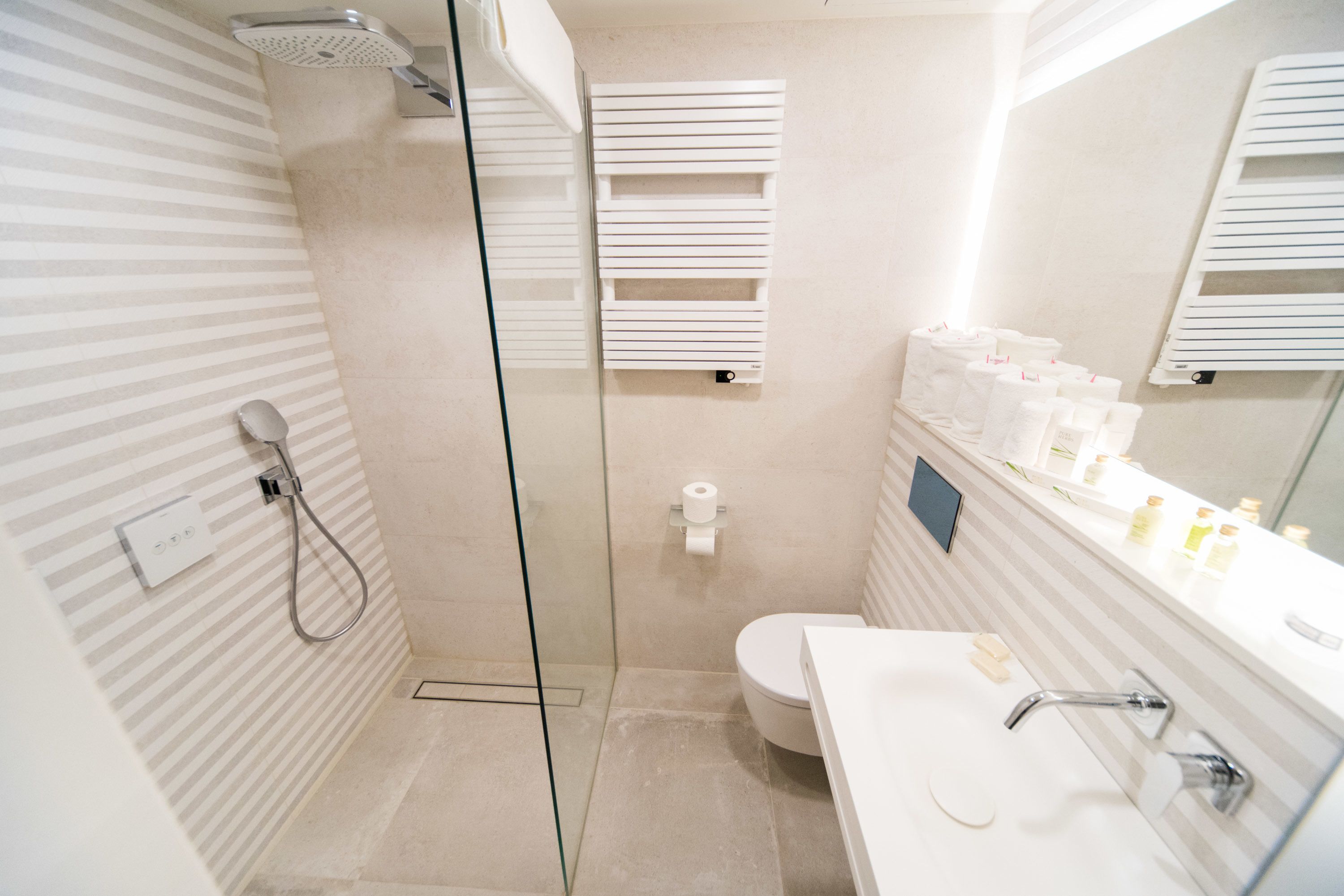 A modern bathroom with a glass-enclosed shower, a toilet, and a sink with a mirror.
