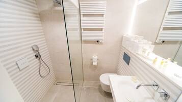 A modern bathroom with a glass-enclosed shower, a toilet, and a sink with a mirror.