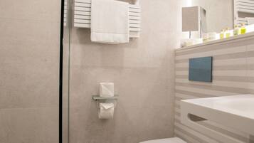 A modern bathroom with a glass shower enclosure, a white toilet, and a vanity with a mirror.