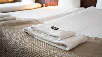 Un lit bien fait, avec une serviette blanche pliée et un petit objet décoratif posé sur le dessus.