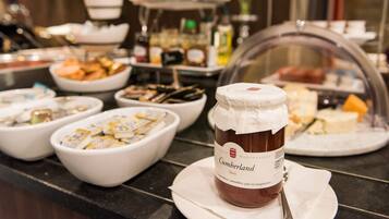 A buffet with various food items, including a jar of Cumberland Saus, bowls of food, and a glass display case.