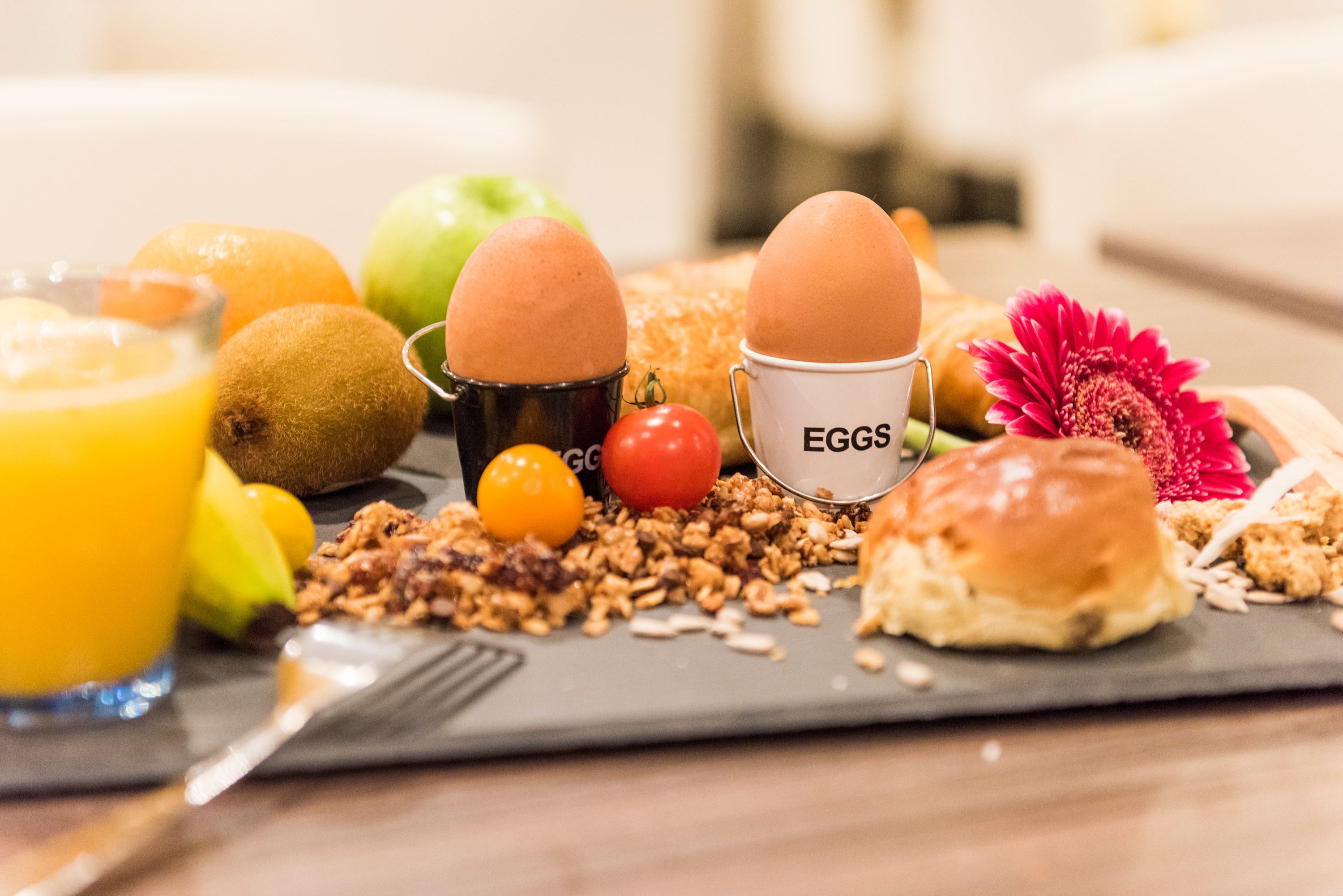 Un plateau de petit-déjeuner avec des œufs, des fruits et du granola.