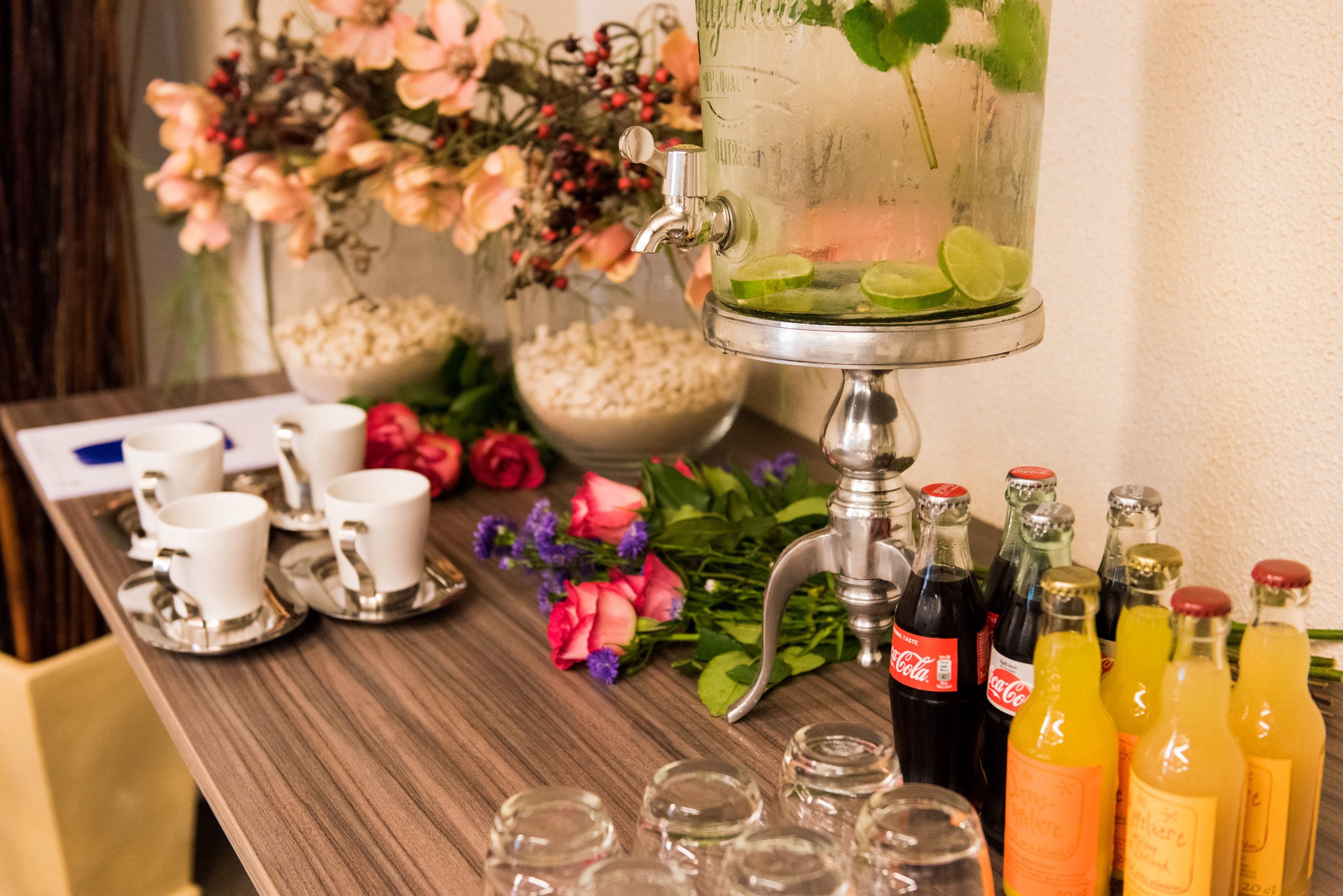 Una zona de bar con un hielera grande, vasos y botellas de bebidas.
