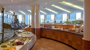 Un buffet proposant une variété de plats, un comptoir incurvé et une vue sur l’extérieur grâce à de grandes fenêtres.