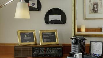 A room with a wooden desk, a vintage radio, a framed award, and wall-mounted records.