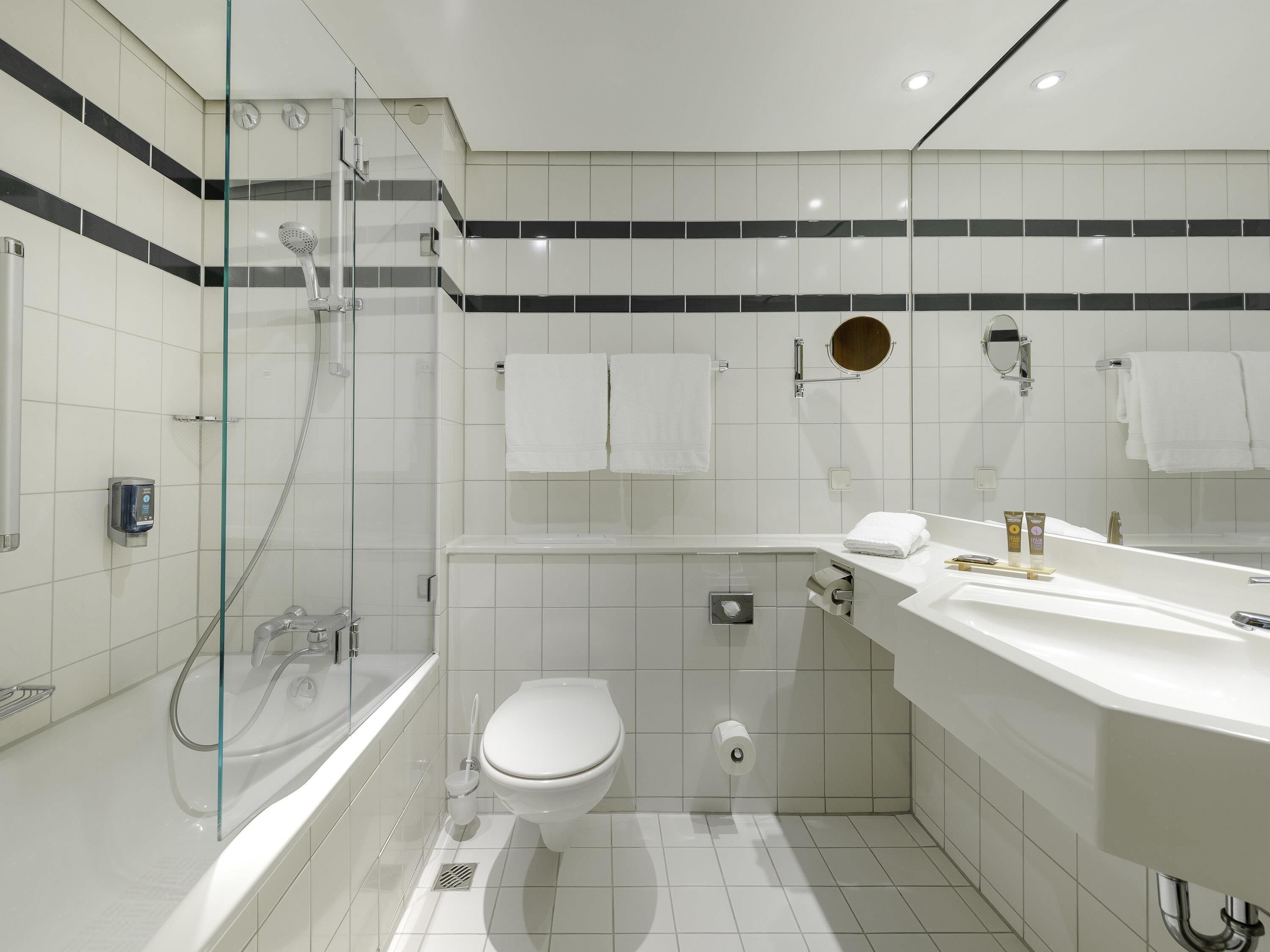 A modern bathroom with a glass-enclosed shower, a white toilet, and a vanity with a mirror.