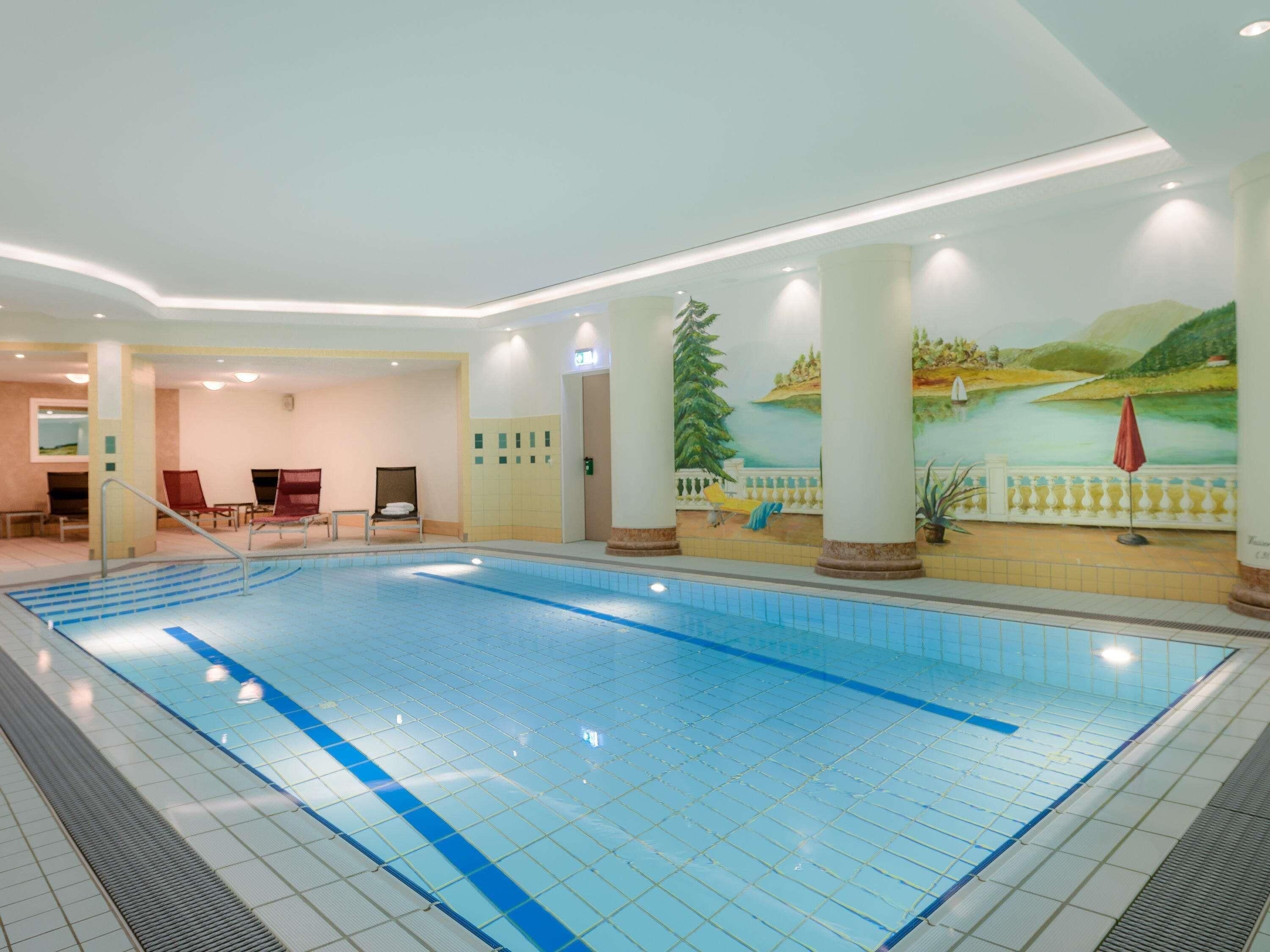 A swimming pool with a tiled floor and a mural of a landscape on the wall.