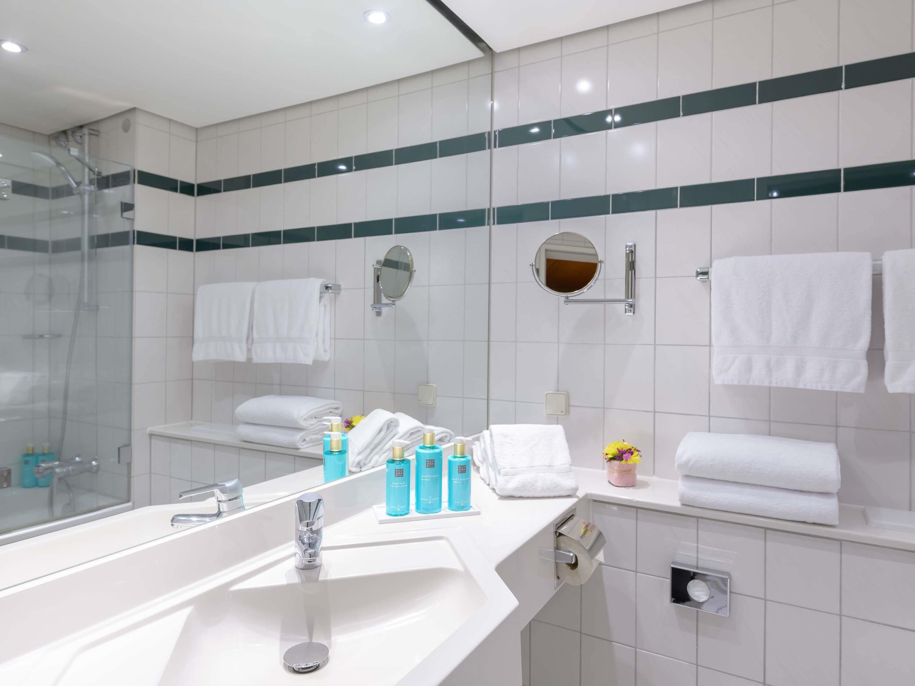 A modern bathroom with a large sink, a shower, and two mirrors.