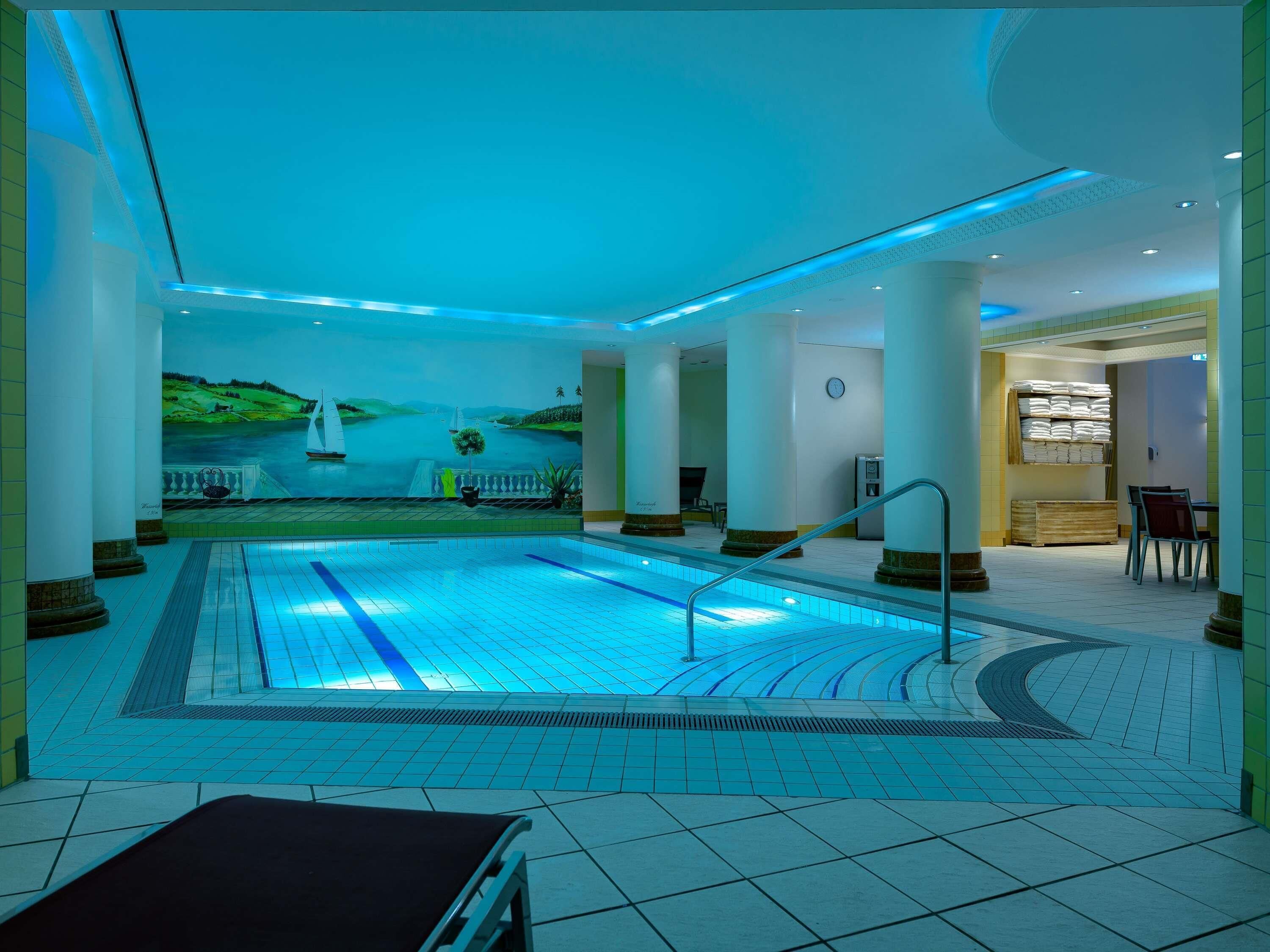 A swimming pool with a mural, columns, and a seating area.