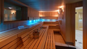 Un sauna avec des bancs en bois, un grand miroir et un sol carrelé.
