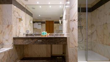 A modern bathroom with a marble vanity, a glass shower enclosure, and a wooden door.